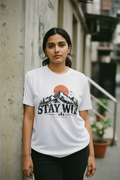 Woman standing against a wall in a white Stay Wild printed sports jersey t-shirt