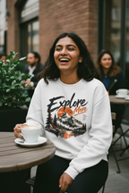 Woman at an outdoor cafe in a white Explore More printed fleece sweatshirt